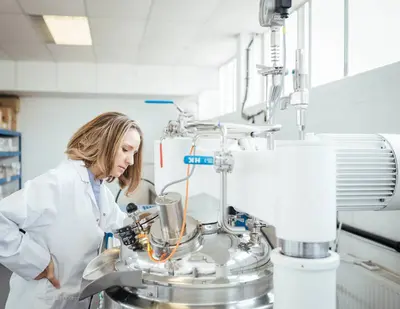 Sarah in a lab coat at a machine in the Pai factory